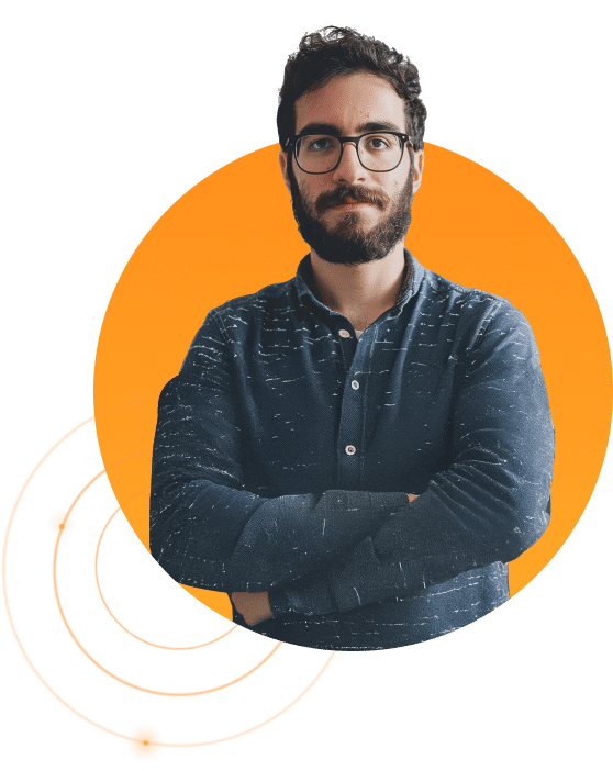 A man with dark hair, beard, and glasses stands with arms crossed, wearing a dark button-up shirt. He is against an abstract background with orange circles and dot patterns, resembling an atomic structure.