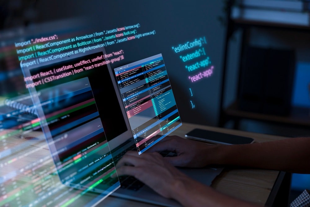A person typing on a laptop with translucent, floating code windows and multiple screens displaying colorful programming code.