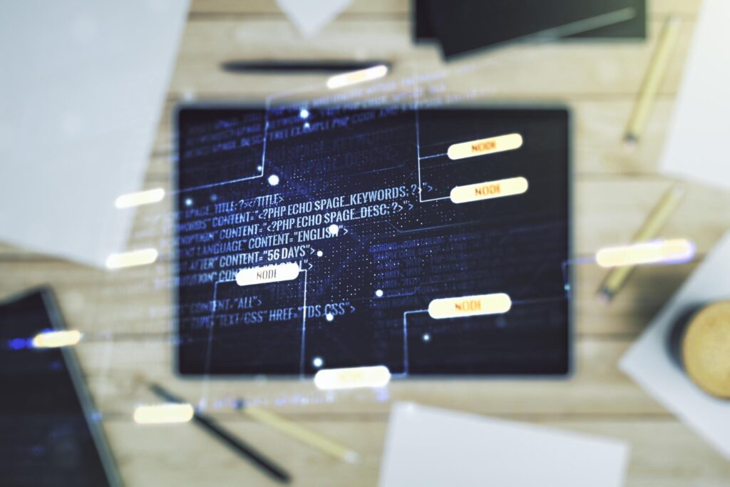 Overhead view of a laptop on a wooden desk showing a dark screen with code and a translucent flowchart of connected rounded rectangles labeled NODE.